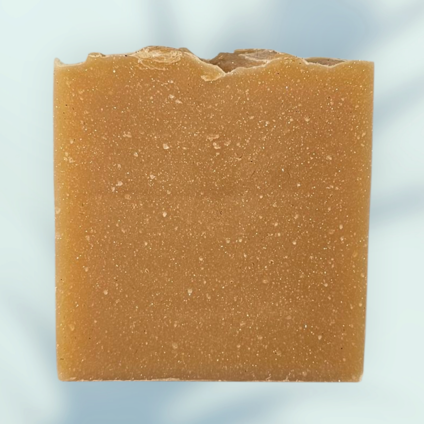 Square bar of brown soap on a light blue background