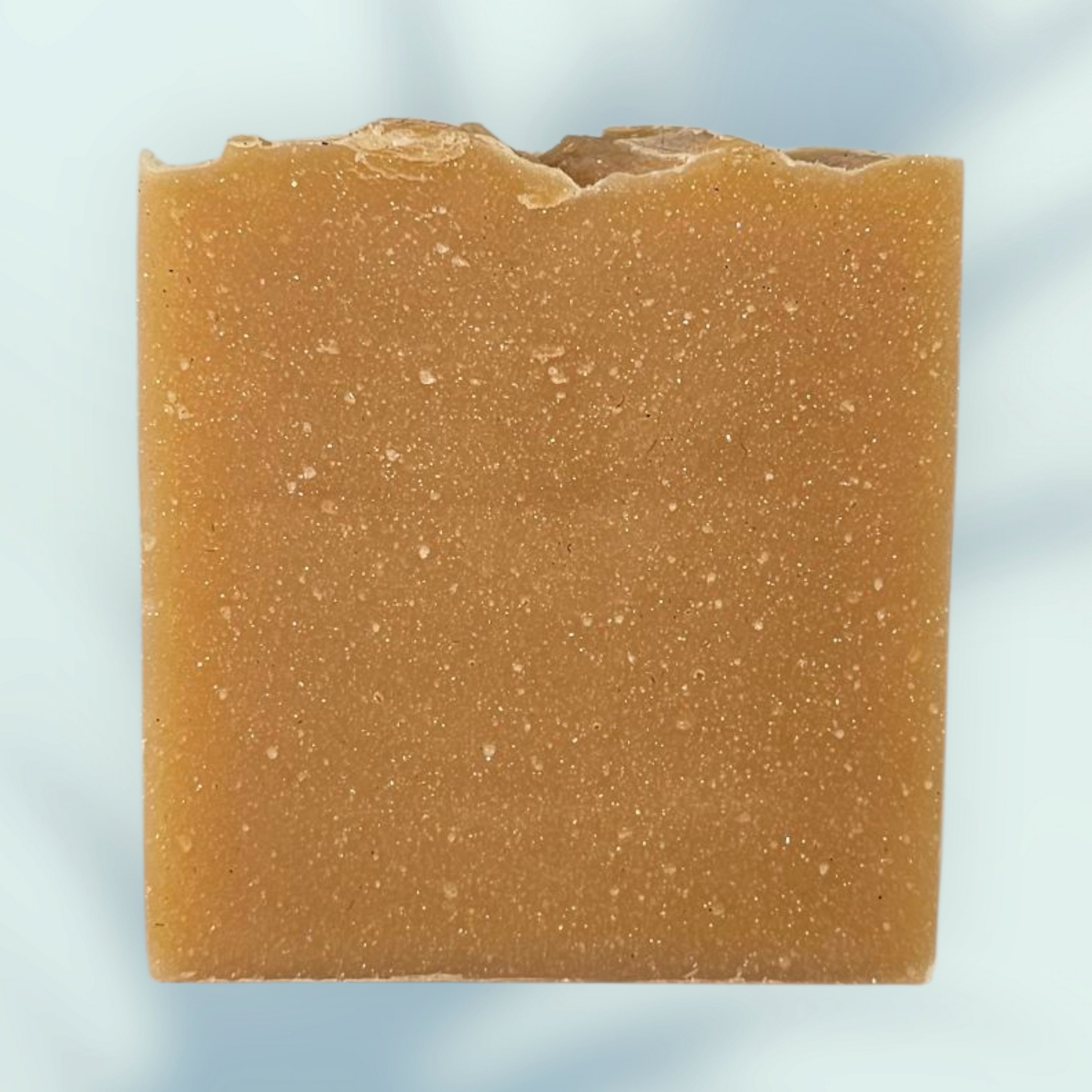 Square bar of brown soap on a light blue background