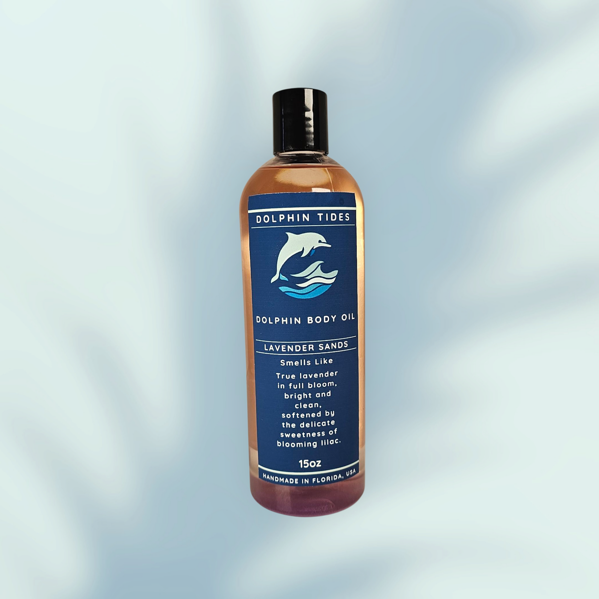 Bottle of Dolphin Tides body oil with a blue label on a light gray background