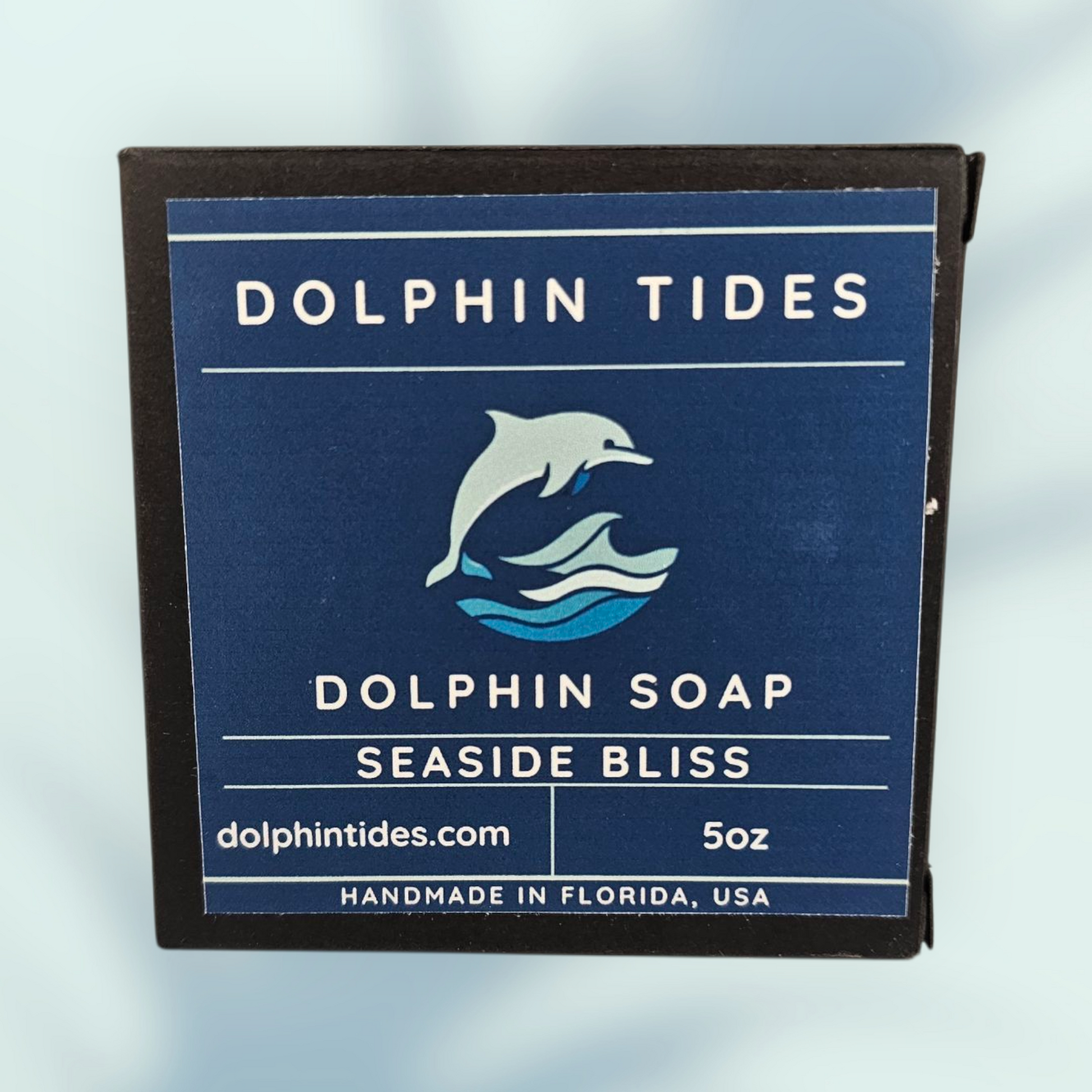 Dolphin Tides soap packaging with branding and product details on a light blue background