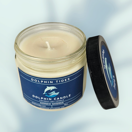Dolphin Tides candle in a glass jar with a blue label on a light gray background
