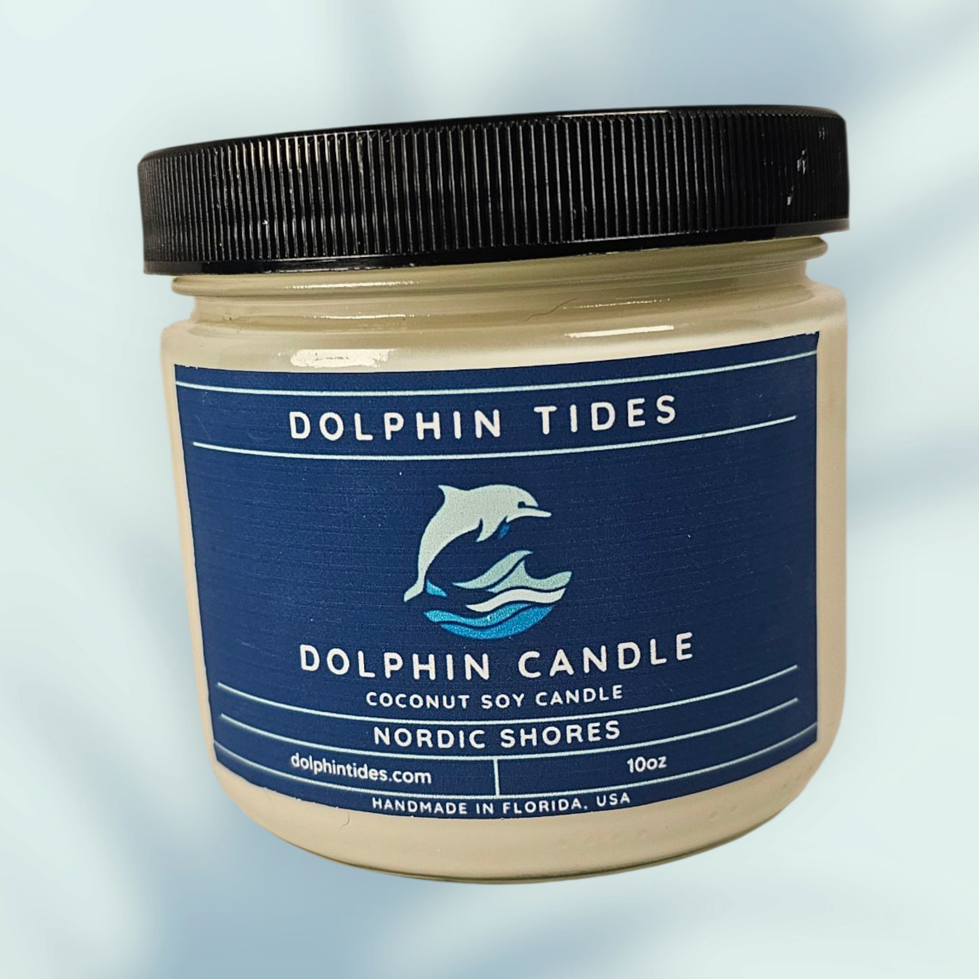 Dolphin Tides candle jar with a blue label on a light blue background