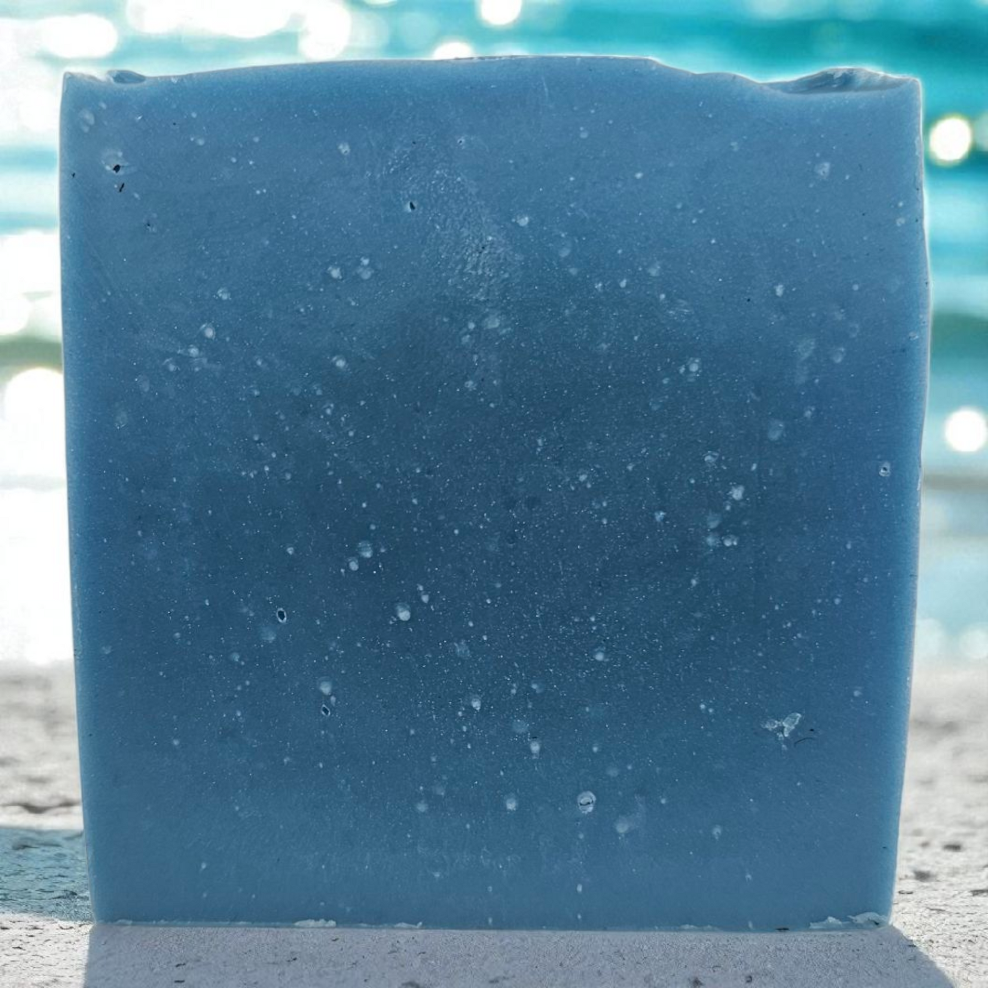 Blue bar of soap with a textured surface on a sandy background