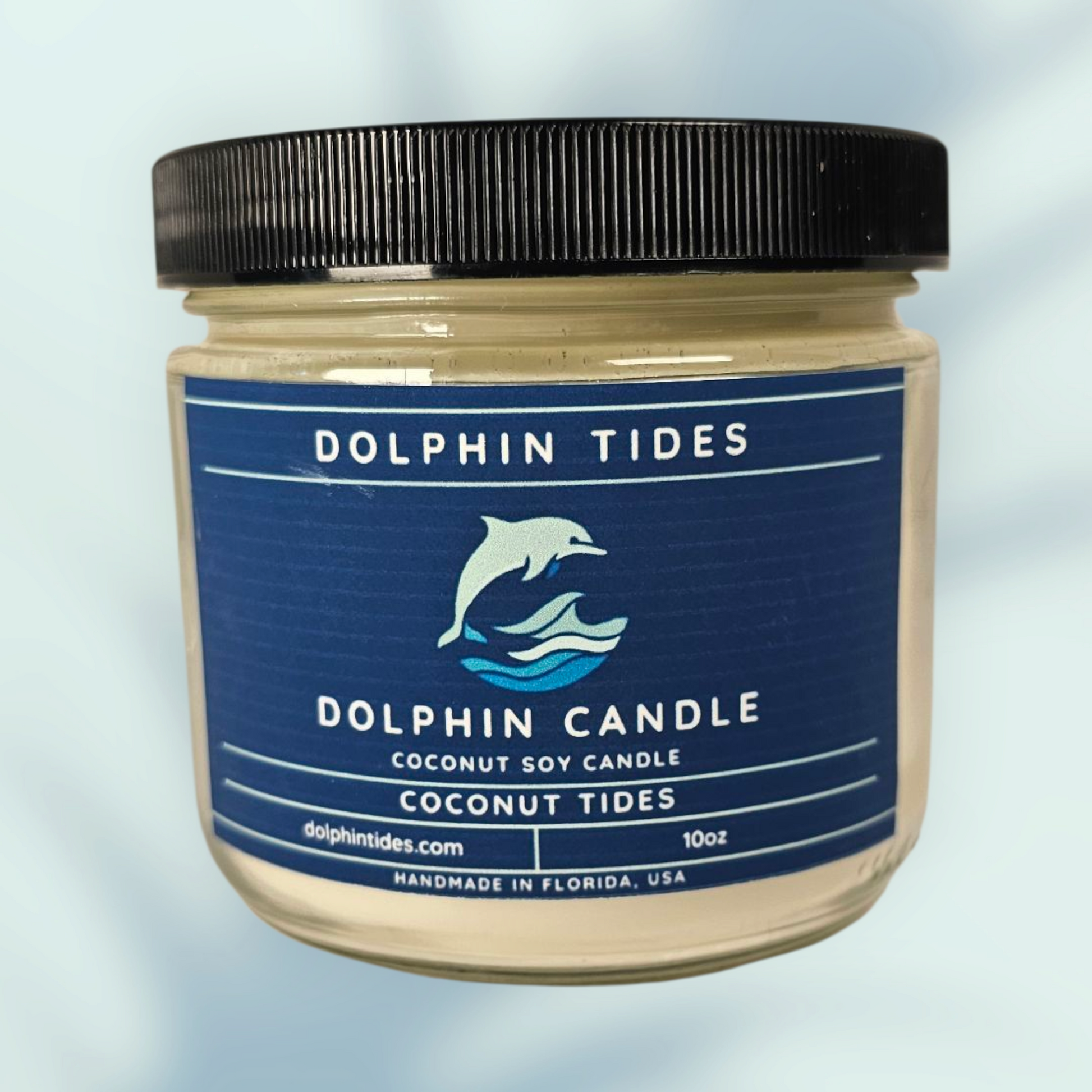 Dolphin Tides candle jar with blue label on a light blue background